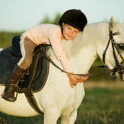 shutterstock_205878118 A small child on a grey pony, hugging her beloved pony club mount that is fed a balanced diet